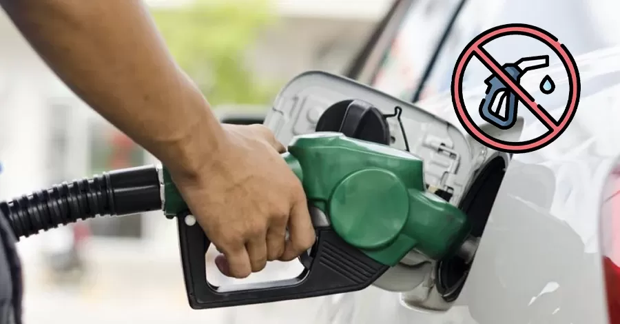 Plano de una mano sosteniendo el surtidor de combustible mientras carga gasolina en el auto